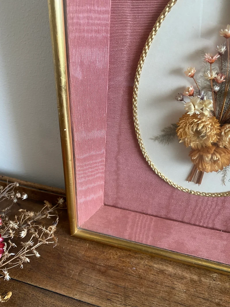 Fleurs séchées encadrées sur fond rose en tissu