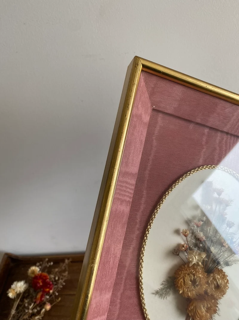 Fleurs séchées encadrées sur fond rose en tissu