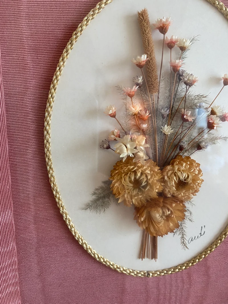 Fleurs séchées encadrées sur fond rose en tissu