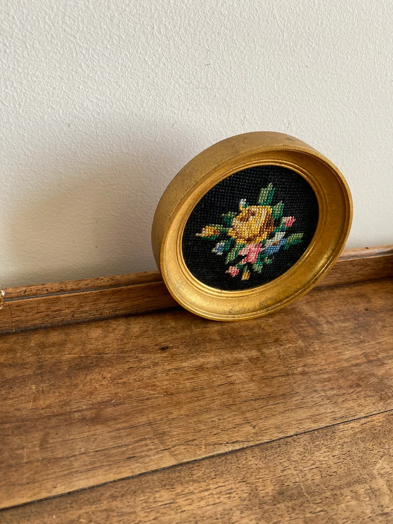 Broderie encadrée sur fond noir cadre rond doré