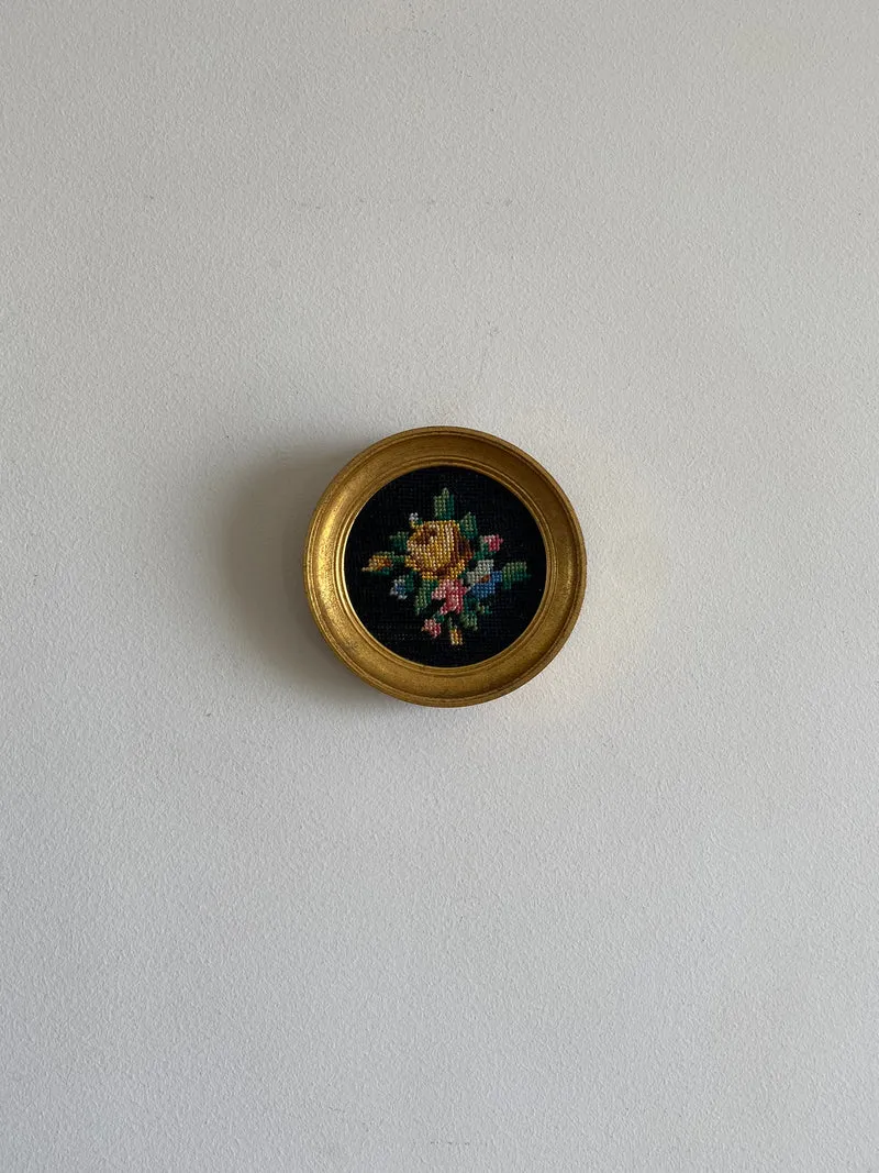 Broderie encadrée sur fond noir cadre rond doré