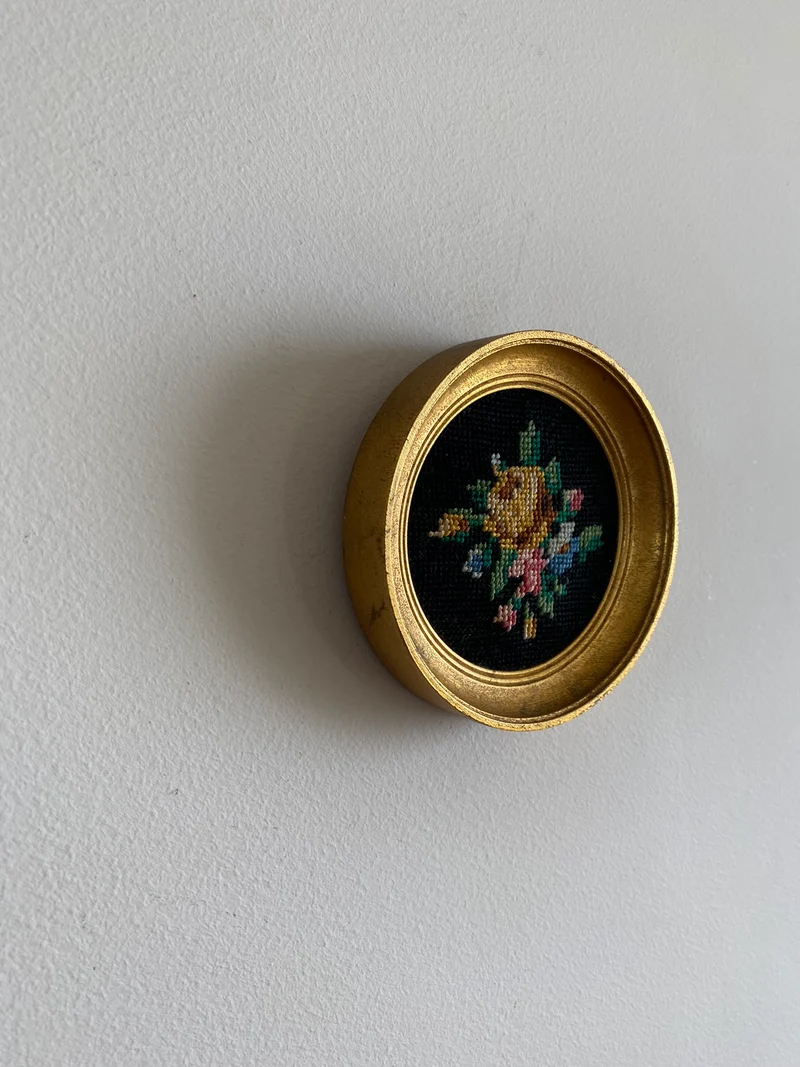 Broderie encadrée sur fond noir cadre rond doré