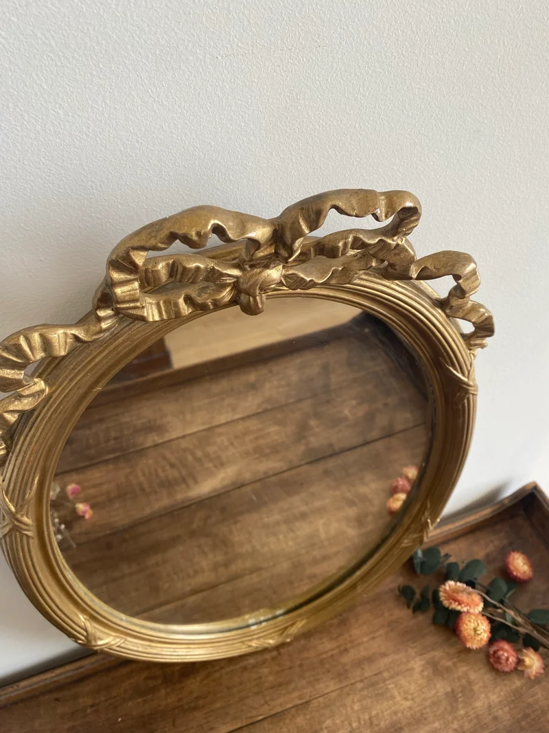 Miroir ovale en bois doré fronton noeud style Louis XVI