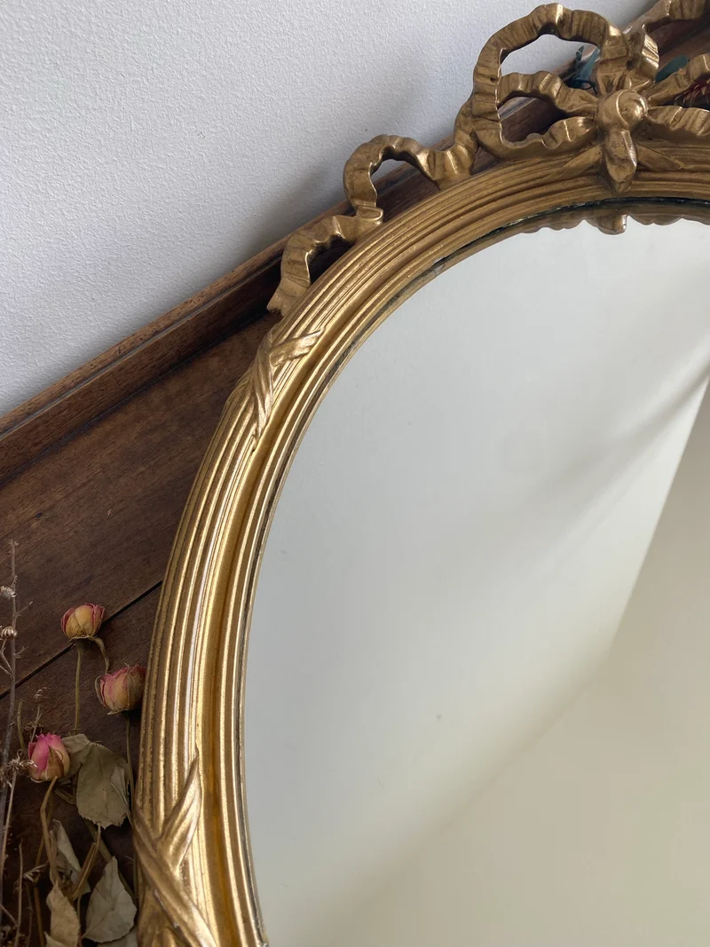 Miroir ovale en bois doré fronton noeud style Louis XVI