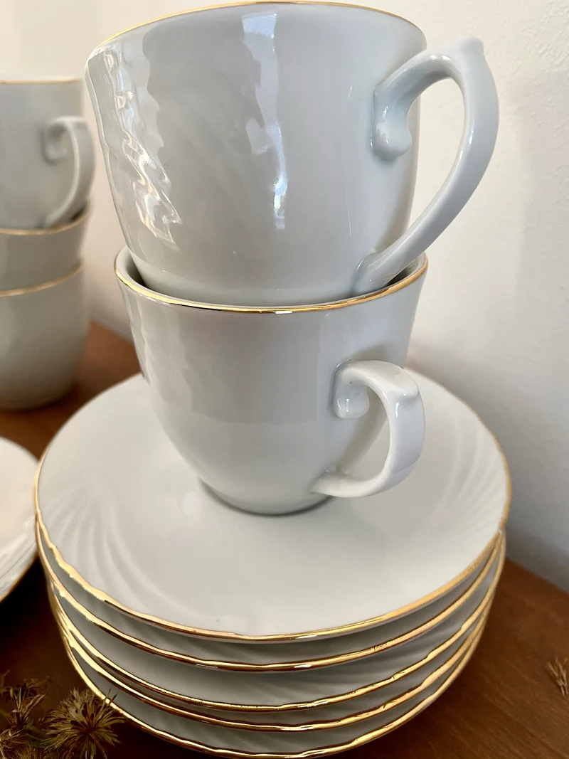 Service à café en porcelaine blanche avec rebords dorés.